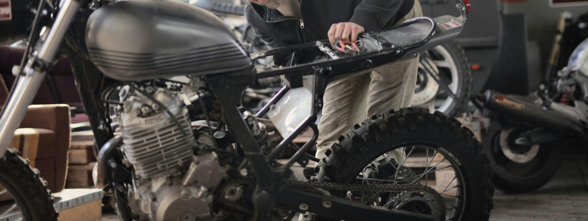 Ein erwachsener männlicher Mechaniker arbeitet in einer Werkstatt im Industriestil an einem Motorrad.