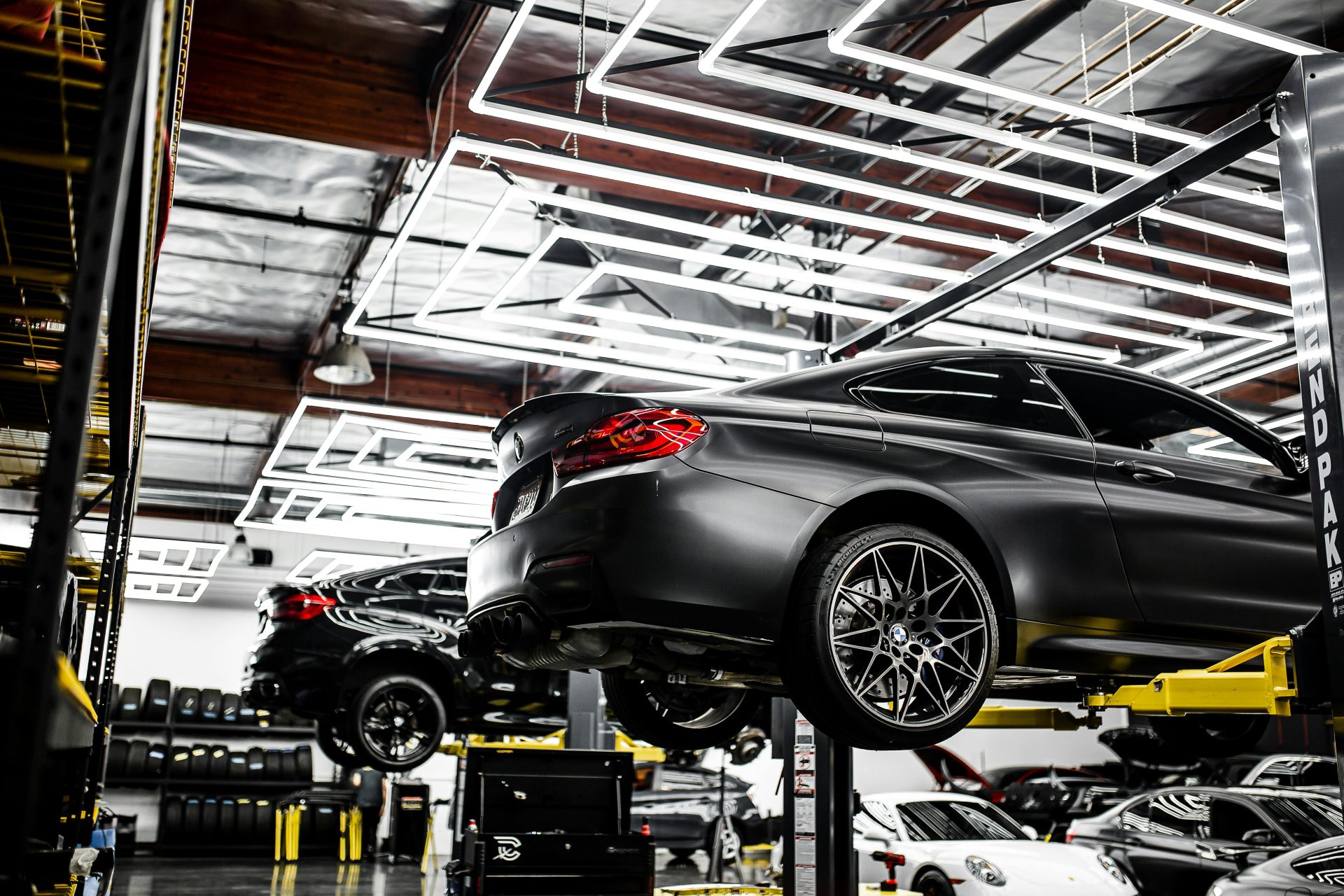 Eine moderne Autowerkstatt, die Fahrzeuge auf Hebebühnen sowie einen gut beleuchteten und aufgeräumten Innenraum präsentiert.